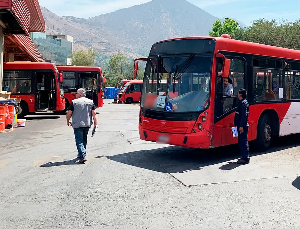 Buses rojos del sistema Red estacionados en un depósito, con un técnico revisando la flota